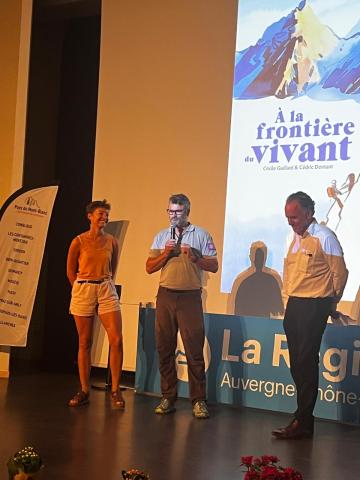 Trois personnes sur une scène avec un micro