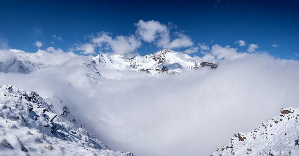 Une montagne enneigée émerge du brouillard
